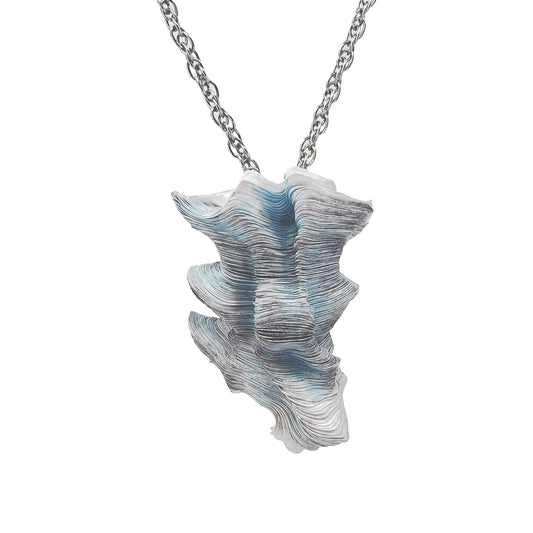 A laser-cut pendant made of Tyvek paper in shades of gray and blue, with a stainless steel neck cord.