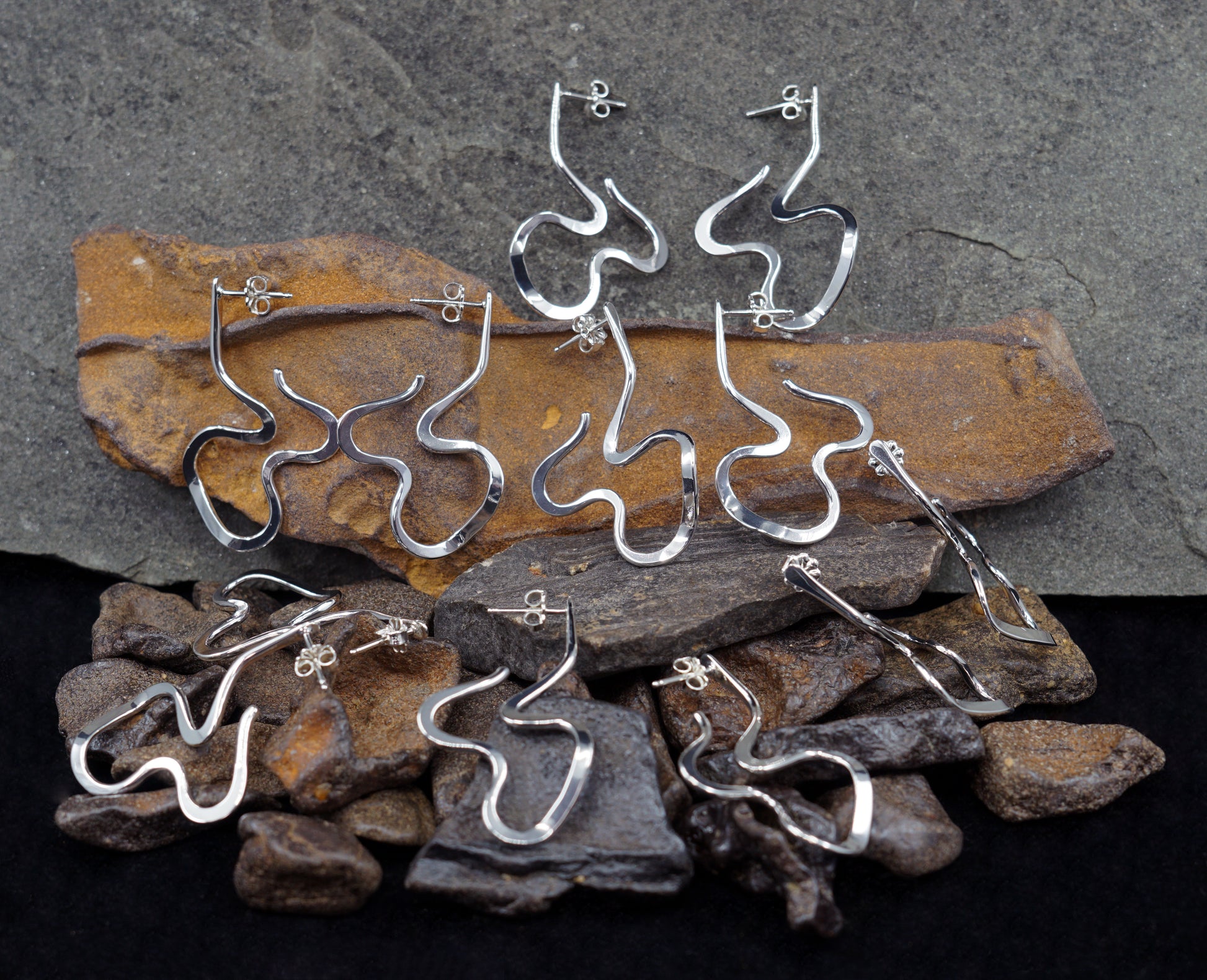 Silver earrings on a bed of stones and rocks