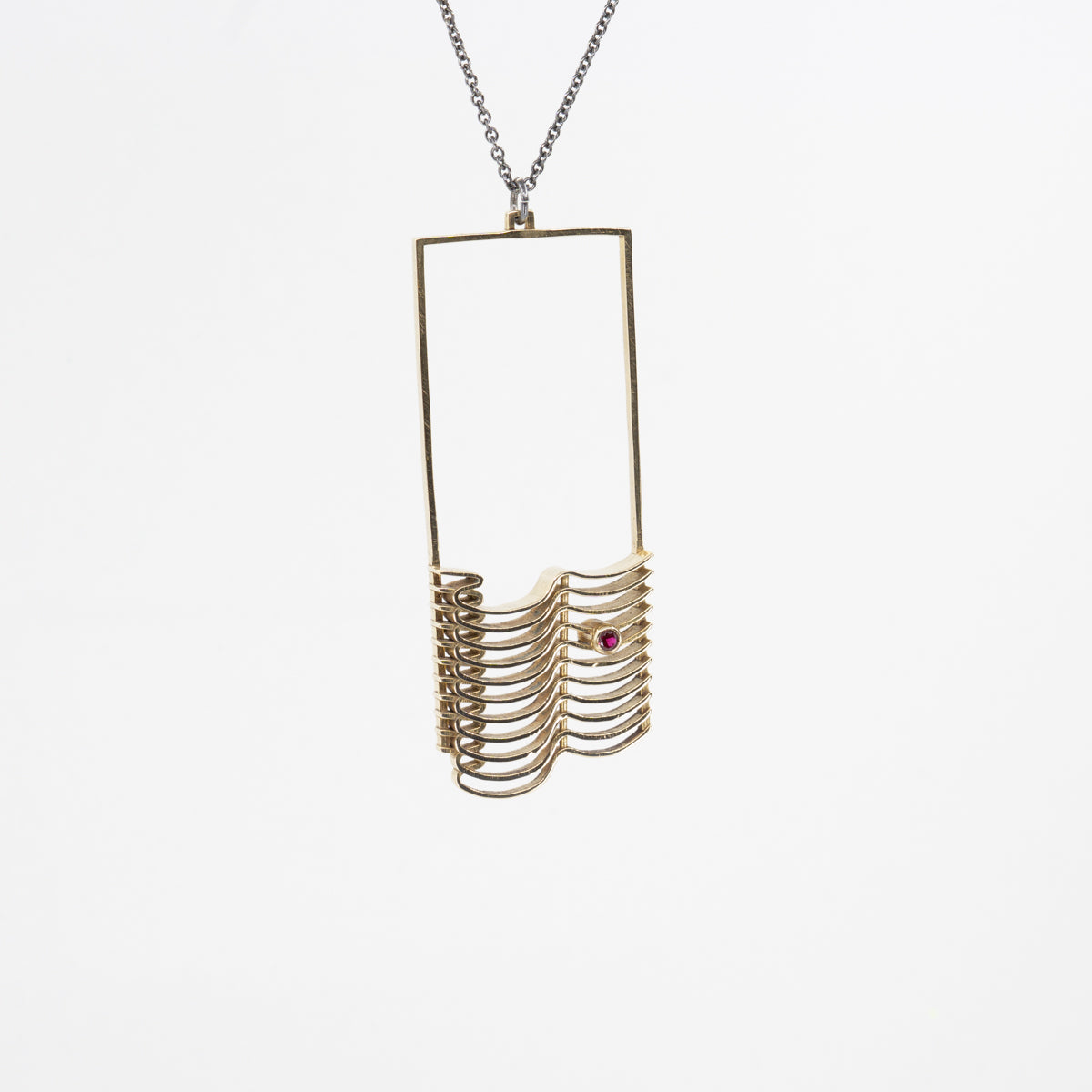 A CAD and cast brass pendant with a chain necklace, featuring a faceted round simulated garnet stone.