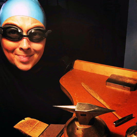 Jeweler at work bench wearing swim cap and goggles